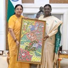 Smt. Savitri Thakur and the President of India holding a framed folk painting between them.