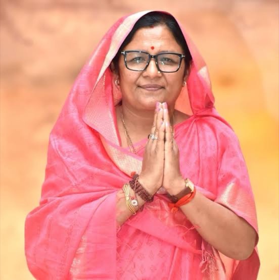 Smt. Savitri Thakur in a pink sari with hands folded in greeting.