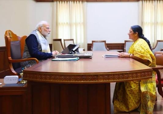 Smt. Savitri Thakur seated across a conference table in discussion with the Prime Minister of India.